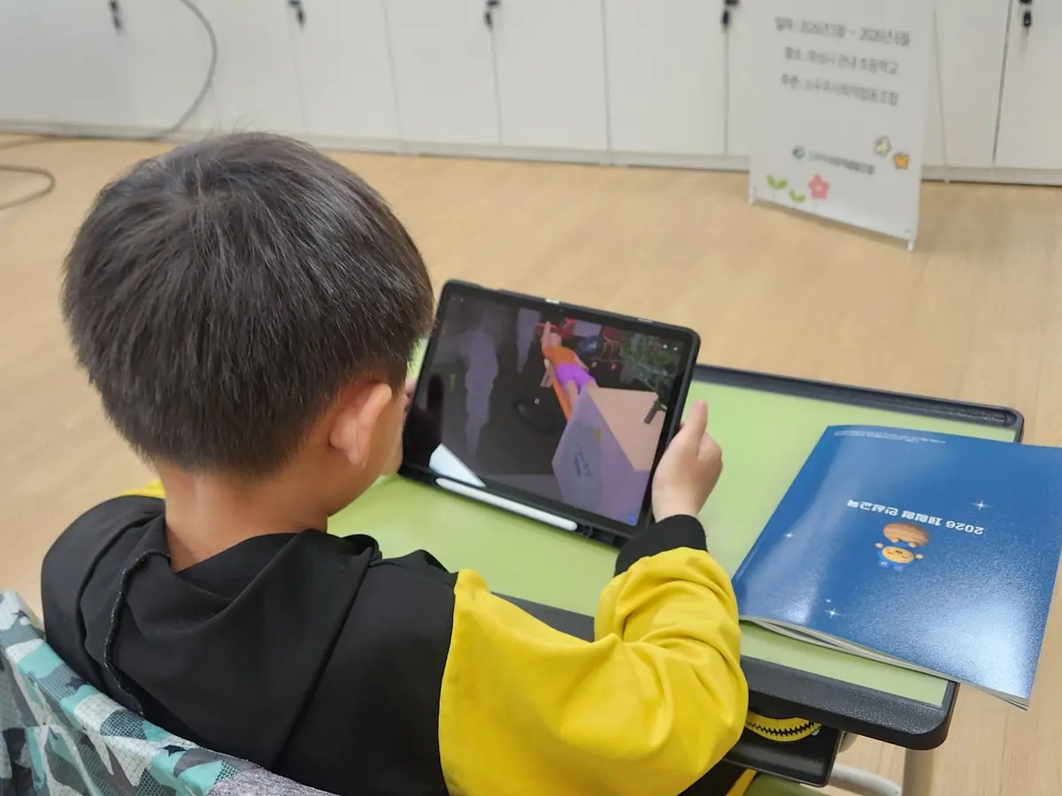화성시 관내 초등학교 디지털 융합 인성교육 수업에서 학생이 태블릿으로 직접 만든 AR 작품을 살펴보는 뒷모습